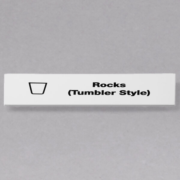 A white rectangular sign with black text that says "Rocks Tumbler Style"