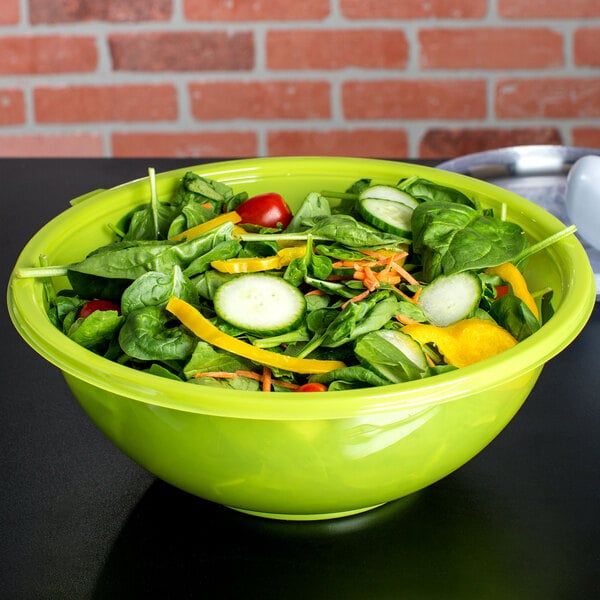 A green Fineline plastic bowl filled with salad on a counter.
