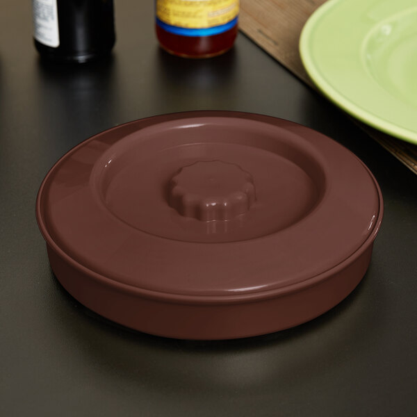 A brown round Carlisle Lennox Tortilla Server with a lid on a table.