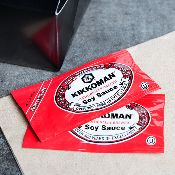 Two red Kikkoman soy sauce packets on a table.