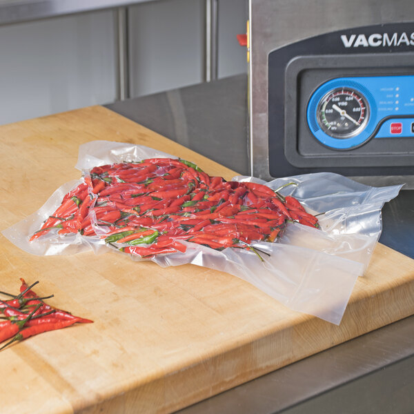 A bag of red peppers on a wooden cutting board.