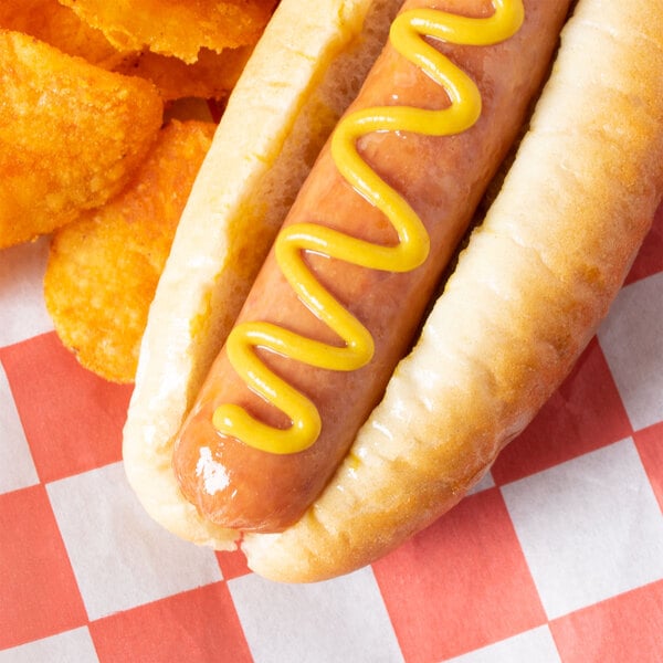 A hot dog with Woeber's yellow mustard on top of a checkered tablecloth.