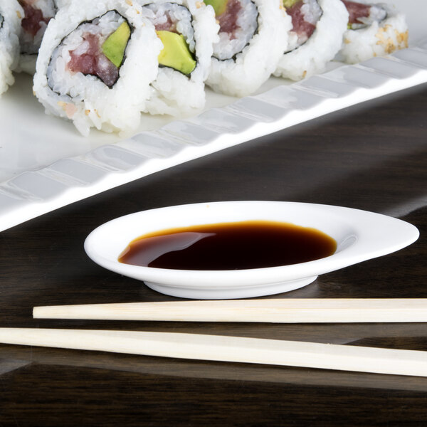 An Arcoroc porcelain dish with sushi and chopsticks on a table.