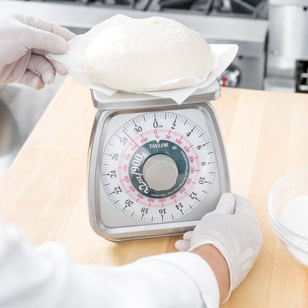 A hand weighing white dough on a Taylor portion scale.