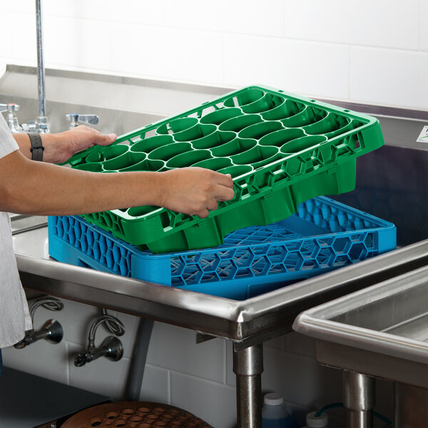 A person holding a green Carlisle glass rack extender over a sink.