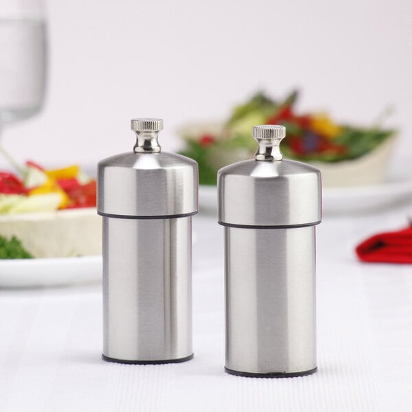 A close-up of two stainless steel salt and pepper mills.
