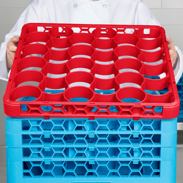 A chef using a red Carlisle glass rack extender to hold red and blue plastic containers.