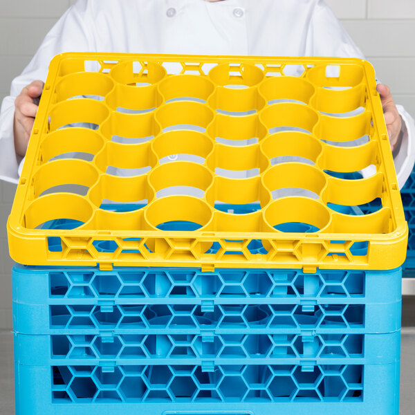 A chef using a yellow Carlisle glass rack extender on a tray.