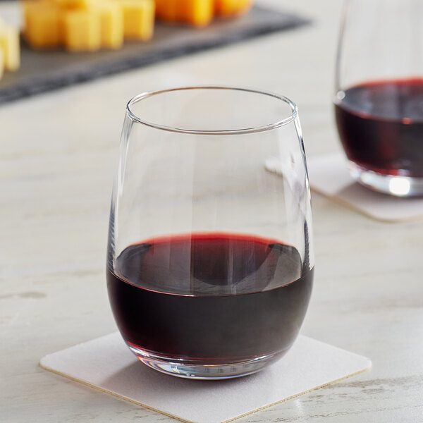 Two Acopa stemless wine glasses filled with red wine on a table.