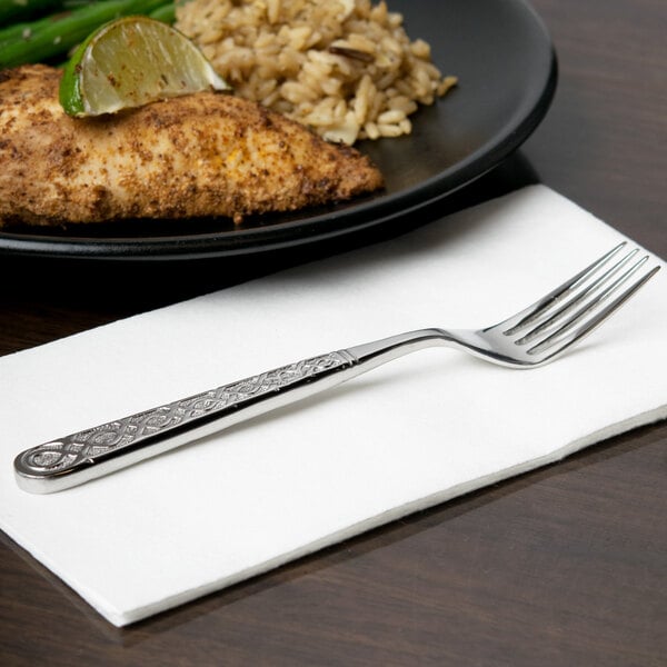 A 10 Strawberry Street Dubai stainless steel salad fork on a napkin next to a plate of food.