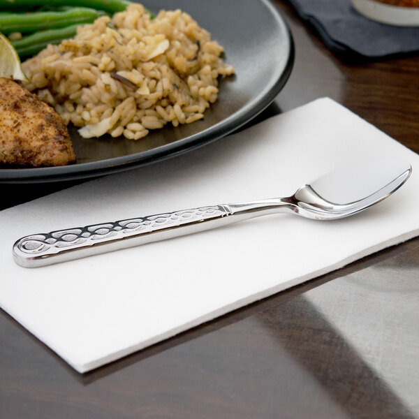 A 10 Strawberry Street stainless steel teaspoon on a napkin next to a plate of food.