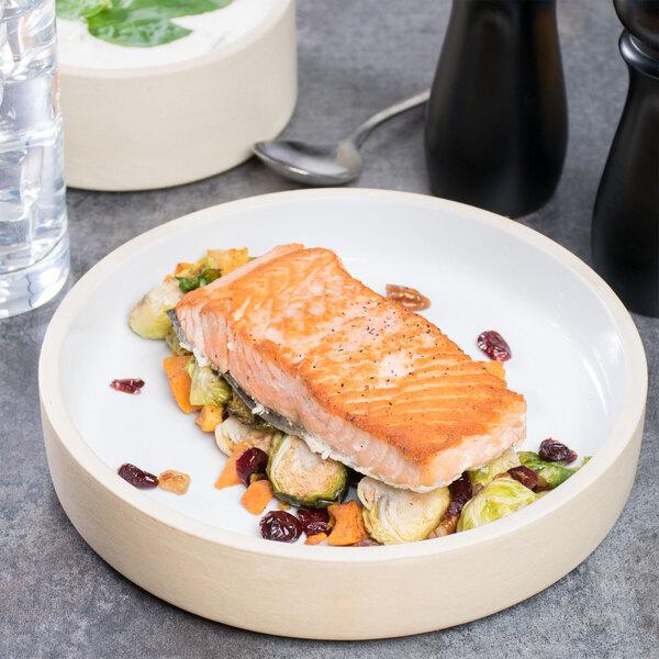 A plate of salmon with cranberries and brussels sprouts on a white table.