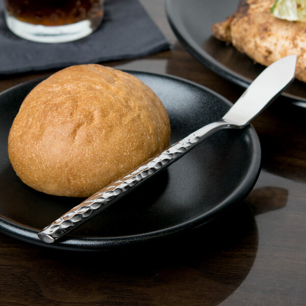 A plate with a roll and a 10 Strawberry Street Hammer Forged stainless steel butter knife on it.