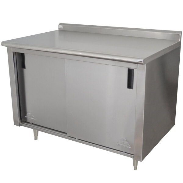 A stainless steel Advance Tabco work table with cabinet base and doors.