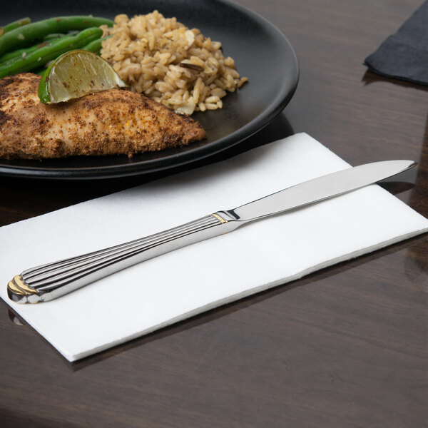 A plate of food with a 10 Strawberry Street Parisian stainless steel dinner knife and fork on a napkin.