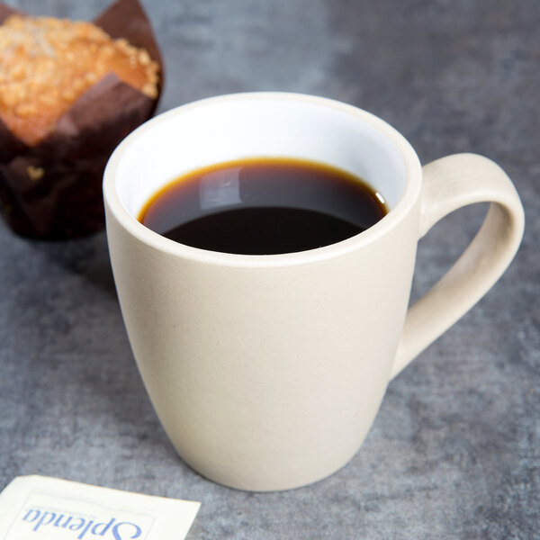 A Chef & Sommelier Geode stoneware mug filled with coffee on a table with a muffin.