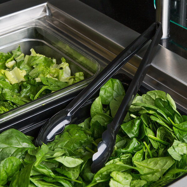 A tray of salad with Cambro black plastic tongs.