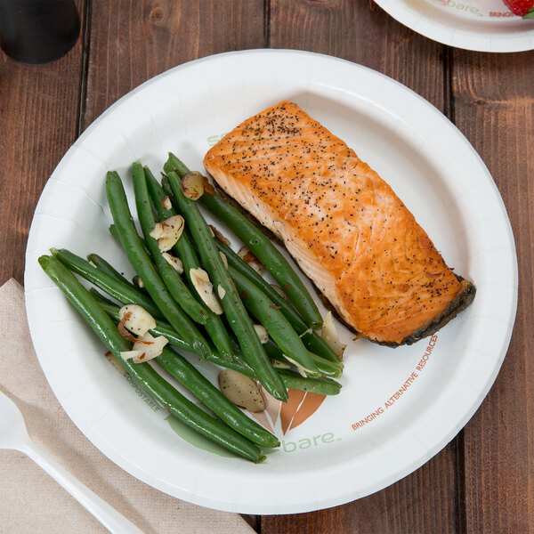 A Bare by Solo medium weight paper plate with a piece of salmon and green beans on a table.