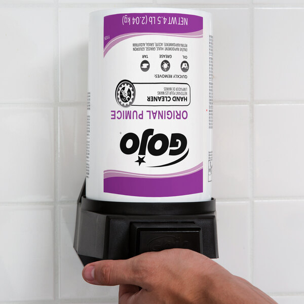 A hand holding a white and purple GOJO container with black text.