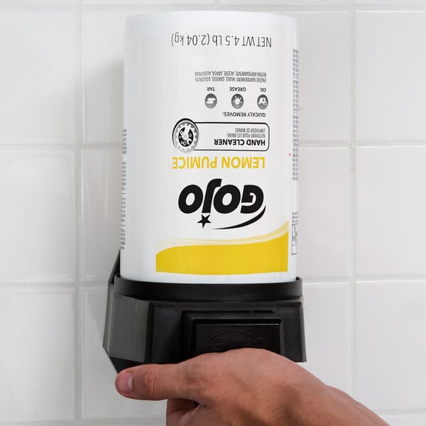 A hand holding a white can of GOJO Lemon Pumice Hand Cleaner with a black and yellow label.