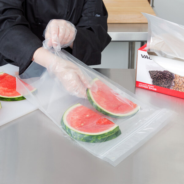 A hand holding a watermelon slice in an ARY VacMaster full mesh vacuum packaging bag.
