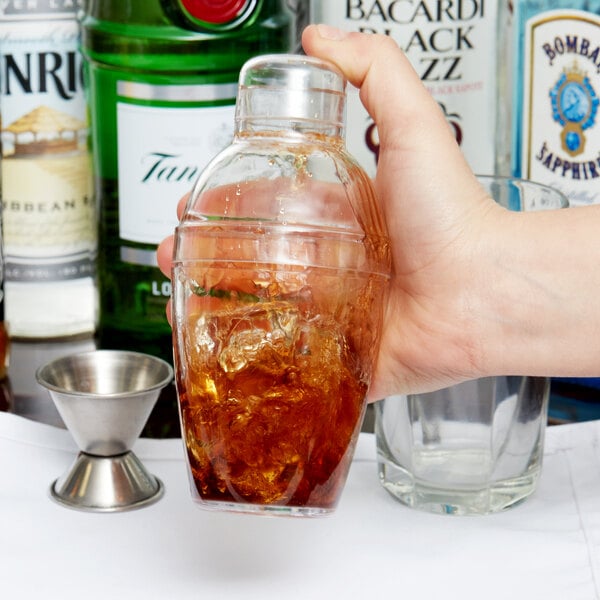 A hand using a Fineline clear plastic shaker to make a cocktail.