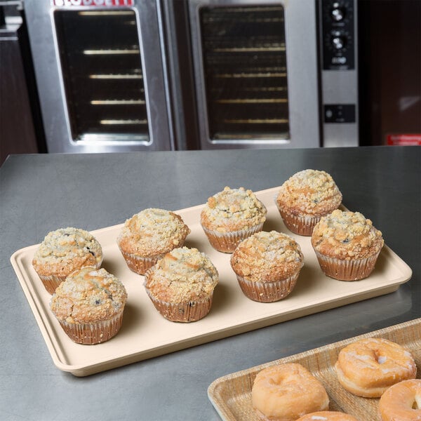 A beige MFG Tray Supreme Display Tray holding muffins on a counter in a bakery display.
