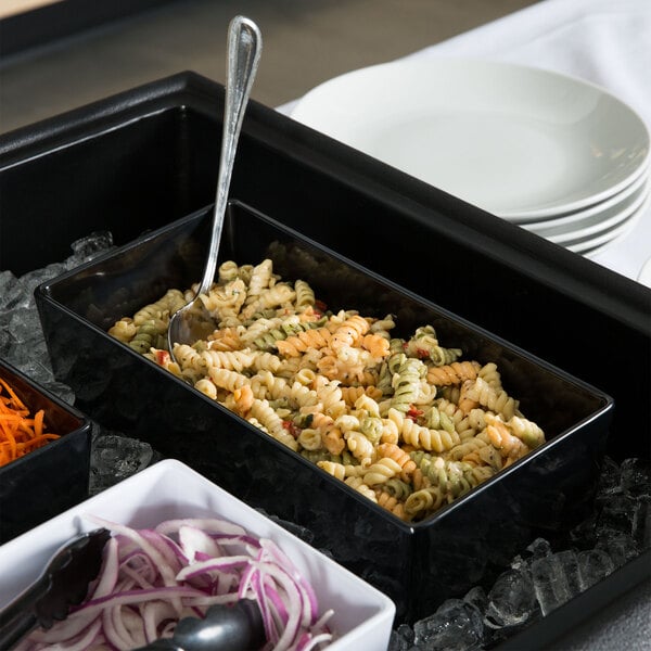 A Tablecraft black melamine bowl filled with pasta on a salad bar table.