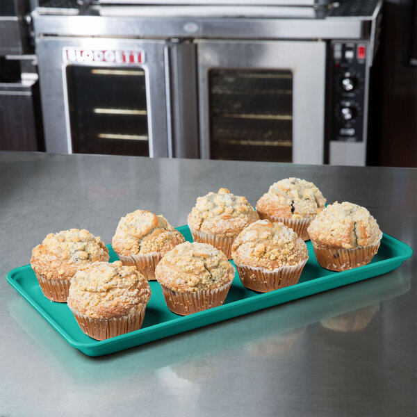 A MFG Tray mint green fiberglass market tray filled with muffins on a counter.