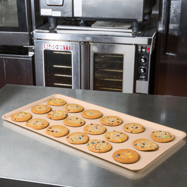 A MFG Tray peach fiberglass display tray of cookies on a counter.