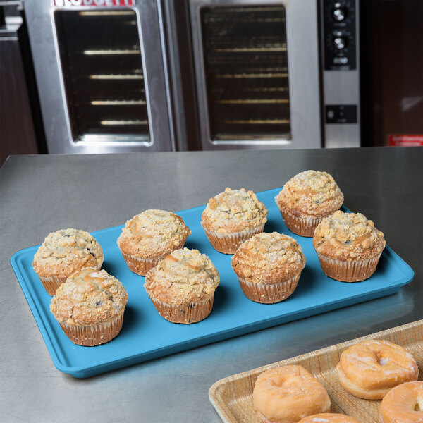 A sky blue MFG Fiberglass Supreme Display Tray holding muffins on a counter.