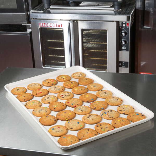 An MFG Tray eggshell fiberglass display tray holding cookies with multicolored sprinkles on a counter.
