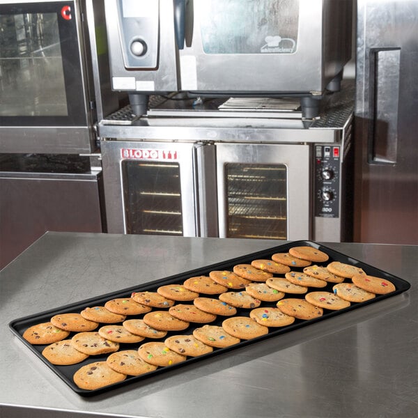 A black MFG Fiberglass Supreme Display Tray holding cookies on a counter.