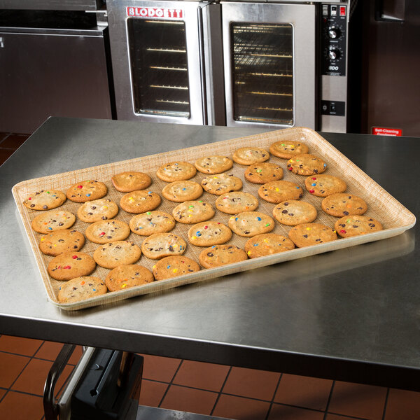 A MFG Tray Rattan fiberglass market display tray of cookies on a kitchen counter.