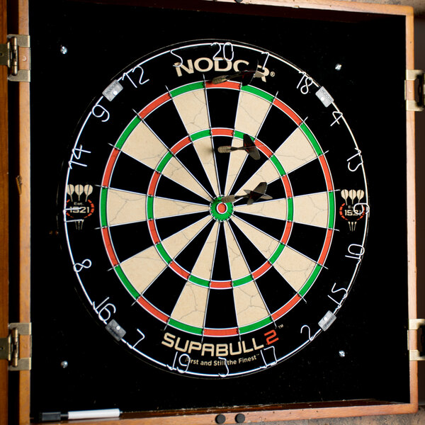 A Nodor staple-free bristle dartboard with darts in the center.