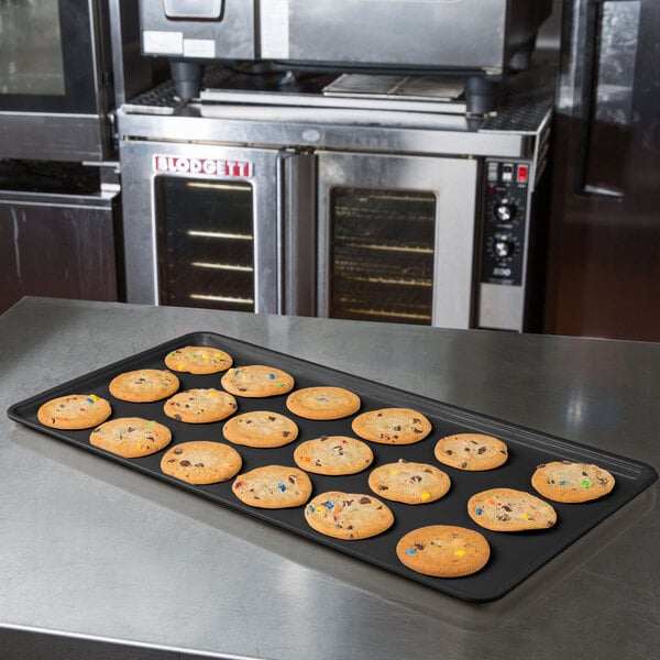 A MFG Tray black fiberglass display tray of cookies on a counter.