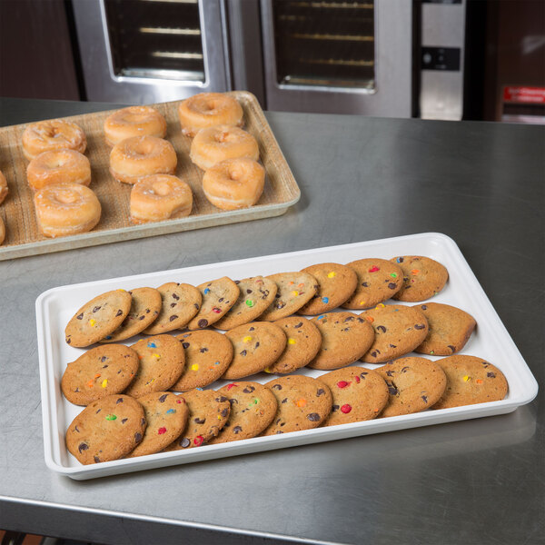 A white MFG Tray Supreme Display Tray holding cookies and donuts on a table.