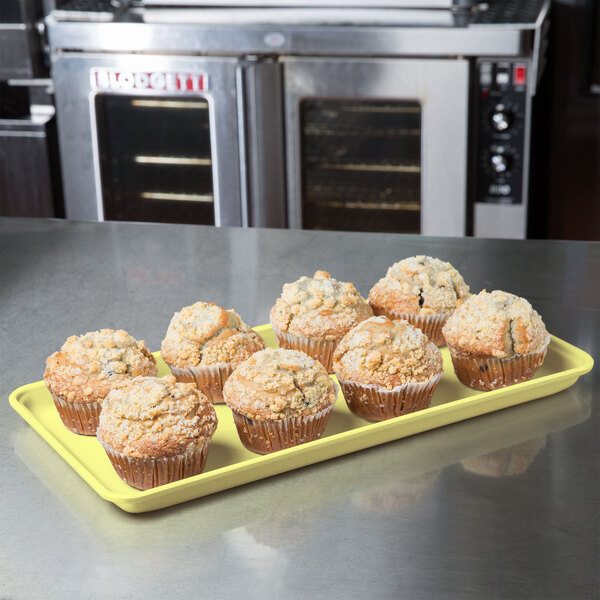 A yellow MFG Fiberglass Supreme Display Tray holding muffins on a counter.