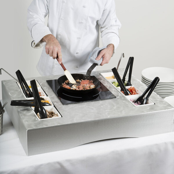 A chef cooking food in a Tablecraft countertop induction station kit.