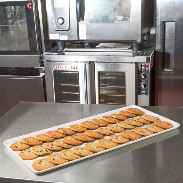A row of cookies on a MFG Tray Supreme Display Tray on a counter.