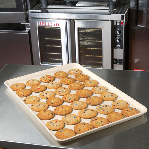 A beige MFG Tray supreme display tray of cookies on a bakery counter.