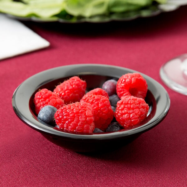A Carlisle Dallas Ware black melamine fruit bowl filled with raspberries and blueberries.