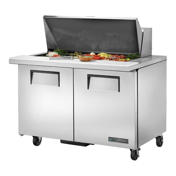 A True 2 door stainless steel refrigerated sandwich prep table on a counter with food.