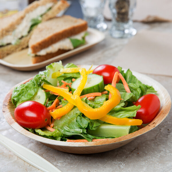 A bowl of salad with sandwiches in it on a table.