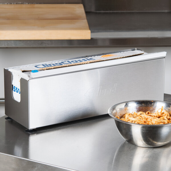 An Edlund stainless steel film and foil dispenser on a stainless steel counter.