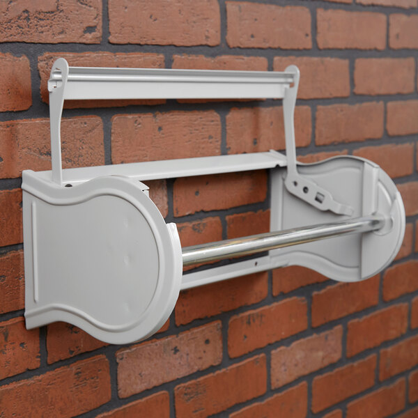 A gray steel Bulman paper dispenser on a brick wall.