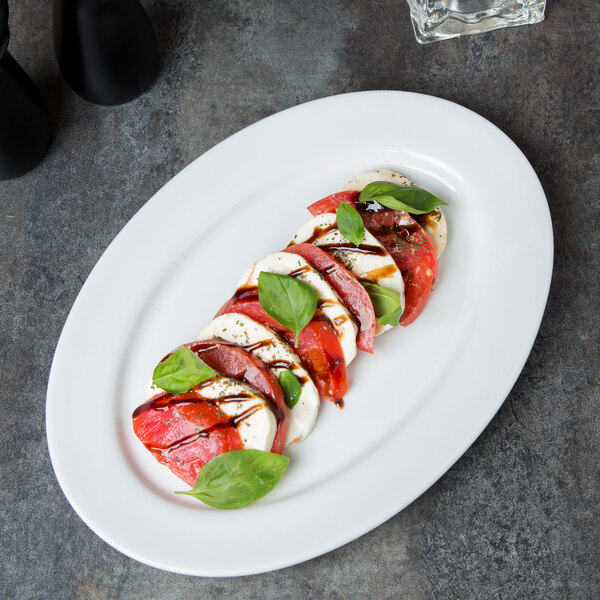 A plate of sliced tomatoes and basil on a Libbey Aluma White porcelain platter.
