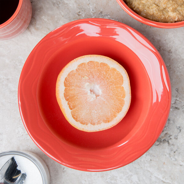A Libbey cayenne grapefruit dish with a spoon and half an orange in it.
