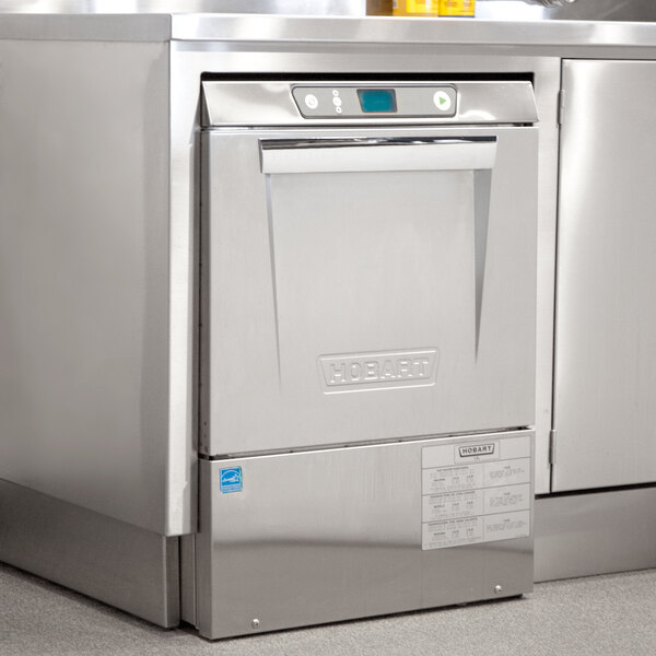 A stainless steel Hobart LXeH-1 undercounter dishwasher on a counter in a professional kitchen.