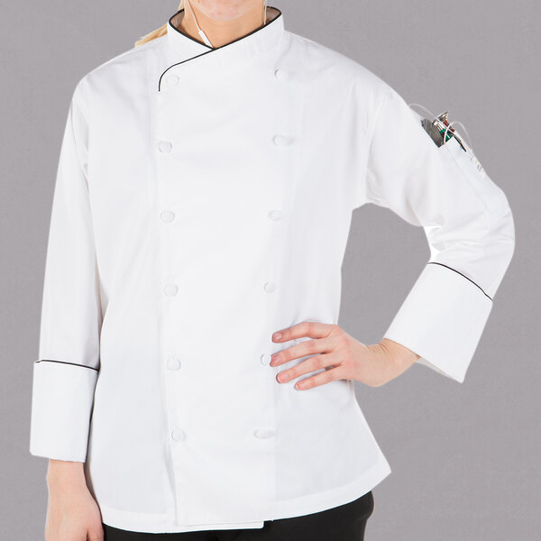 A woman wearing a Mercer Culinary white chef coat with black piping.
